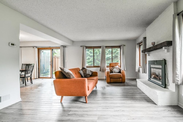7097 Robinwood Bay, Woodbury, MN 55125 - living area featuring a textured ceiling, a brick fireplace, and wood finished floors