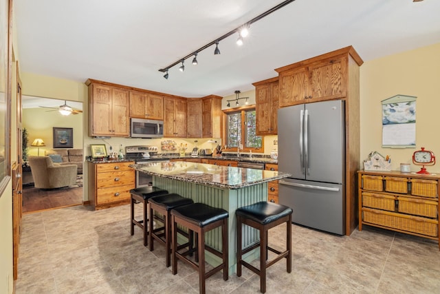 23148 Glenhaven Dr, Nevis, MN 56467 - kitchen featuring stainless steel appliances, a kitchen bar, a center island, a ceiling fan, and dark stone counters
