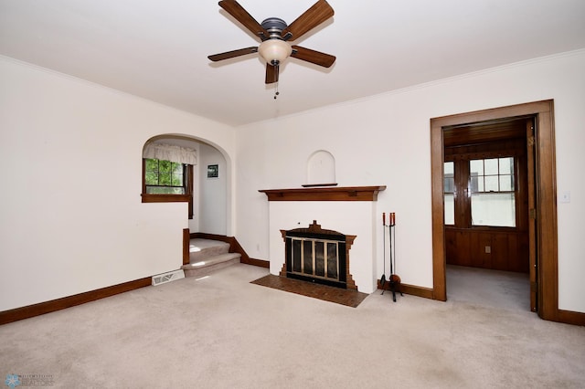 1321 4th St N, Fargo, ND 58102 - unfurnished living room featuring a fireplace with flush hearth, carpet floors, ceiling fan, crown molding, and arched walkways