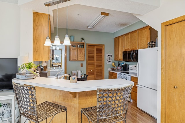 8829 Branson Dr Unit 46, Inver Grove Heights, MN 55076 - kitchen with white appliances, a peninsula, light wood finished floors, light countertops, and a breakfast bar