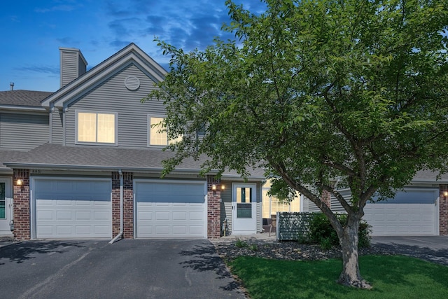 8829 Branson Dr Unit 46, Inver Grove Heights, MN 55076 - view of front facade with driveway, brick siding, a chimney, roof with shingles, and an attached garage
