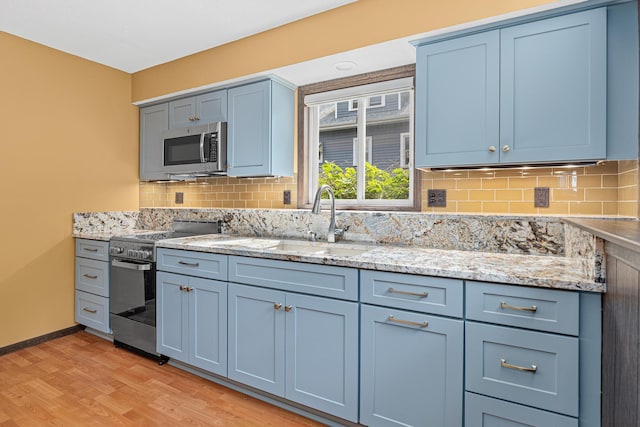 1803 Hubbard Ave, Saint Paul, MN 55104 - kitchen featuring stainless steel appliances, decorative backsplash, light wood finished floors, and light stone counters