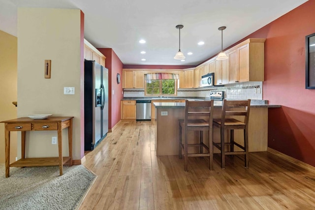 7270 Stone Rdg, Crow Wing Twp, MN 56401 - kitchen featuring appliances with stainless steel finishes, a peninsula, light wood finished floors, tasteful backsplash, and dark countertops