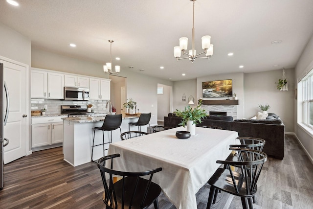 9266 26th St NE, Saint Michael, MN 55376 - kitchen featuring appliances with stainless steel finishes, dark wood finished floors, a chandelier, decorative backsplash, and white cabinetry