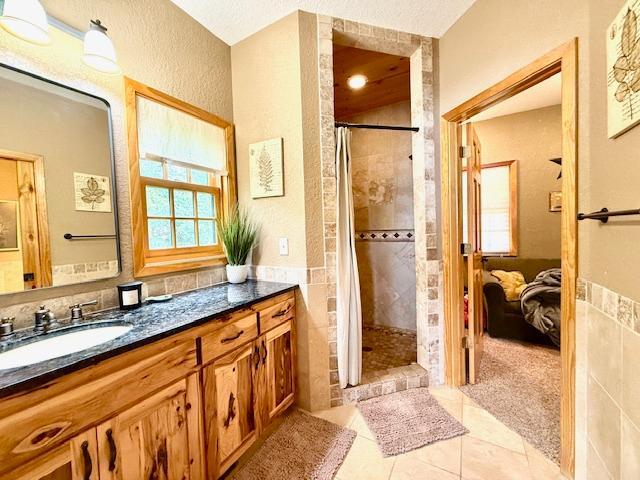 49512 202nd Pl, Shamrock Twp, MN 55760 - ensuite bathroom with vanity, a tile shower, tile patterned floors, and a textured wall