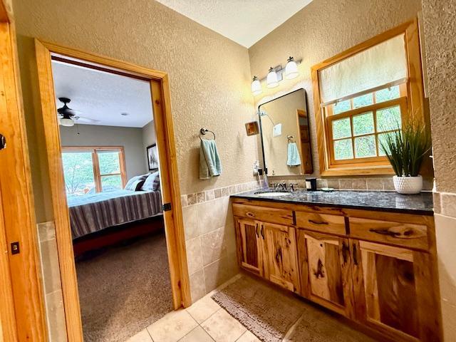 49512 202nd Pl, Shamrock Twp, MN 55760 - bathroom featuring a textured wall, ensuite bathroom, vanity, tile patterned floors, and plenty of natural light