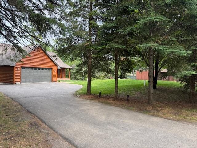 49512 202nd Pl, Shamrock Twp, MN 55760 - view of front facade with faux log siding, driveway, roof with shingles, a front lawn, and a garage