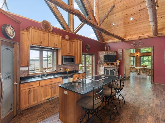 2406 Augusta Rd, Fair Haven Twp, MN 55382 - kitchen featuring stainless steel appliances, brown cabinetry, a breakfast bar area, a fireplace, and high vaulted ceiling
