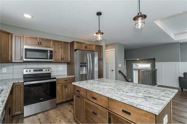 2105 Elk Run Dr SE, Pine Island, MN 55963 - kitchen with appliances with stainless steel finishes, decorative backsplash, wood finished floors, and hanging light fixtures