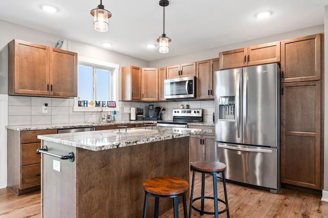 2105 Elk Run Dr SE, Pine Island, MN 55963 - kitchen featuring stainless steel appliances, light wood finished floors, decorative backsplash, a breakfast bar area, and pendant lighting