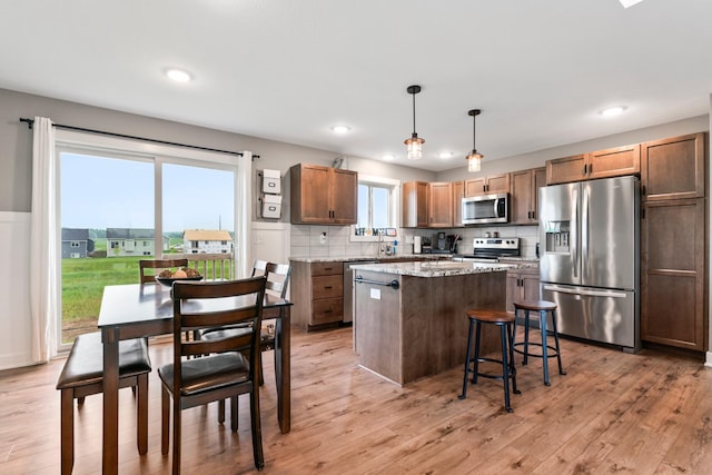 2105 Elk Run Dr SE, Pine Island, MN 55963 - kitchen featuring stainless steel appliances, a center island, light wood-style floors, hanging light fixtures, and a kitchen breakfast bar