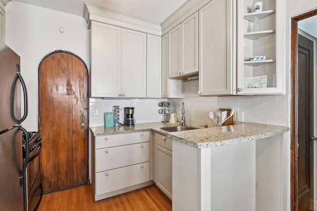 3252 Fremont Ave S Unit 102, Minneapolis, MN 55408 - kitchen with freestanding refrigerator, decorative backsplash, light wood-style flooring, and light stone counters