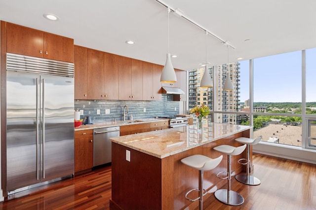 222 2nd St SE Unit 1503, Minneapolis, MN 55414 - kitchen featuring premium appliances, under cabinet range hood, dark wood-style flooring, a kitchen island, and a kitchen breakfast bar