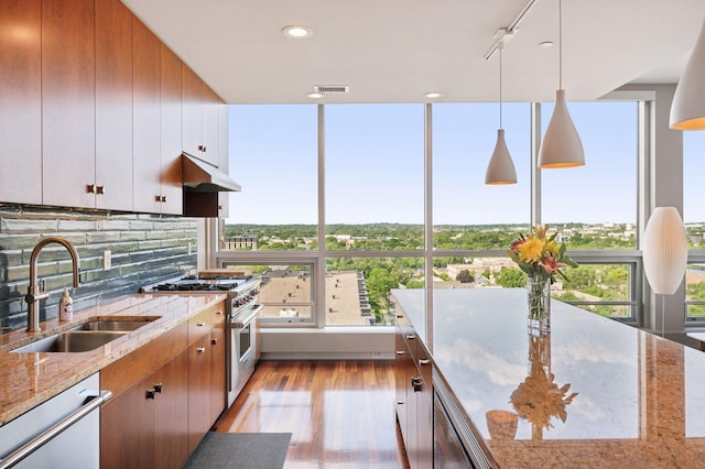 222 2nd St SE Unit 1503, Minneapolis, MN 55414 - kitchen with high end stainless steel range, white dishwasher, light wood finished floors, decorative backsplash, and under cabinet range hood