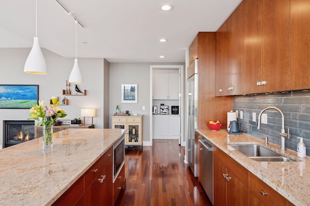 222 2nd St SE Unit 1503, Minneapolis, MN 55414 - kitchen featuring brown cabinetry, dark wood-style floors, stainless steel appliances, tasteful backsplash, and a glass covered fireplace