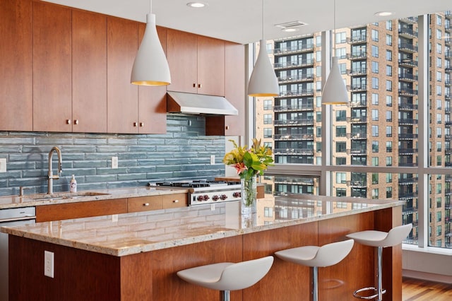 222 2nd St SE Unit 1503, Minneapolis, MN 55414 - kitchen featuring under cabinet range hood, appliances with stainless steel finishes, backsplash, and a kitchen bar