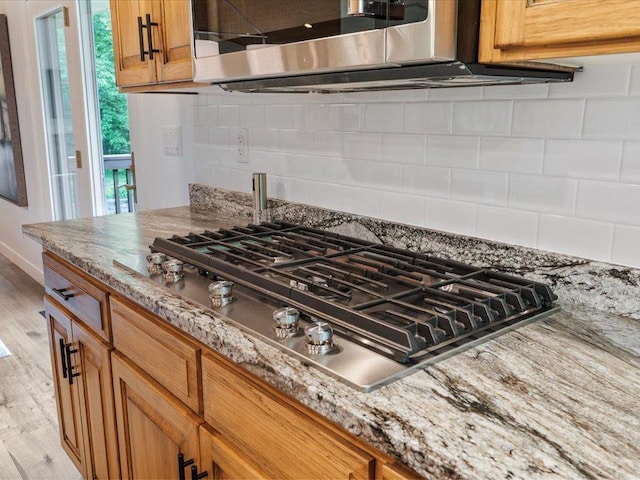 11034 Forest View Ct SW, Nisswa, MN 56468 - kitchen view of appliances with stainless steel finishes, brown cabinetry, light wood-style flooring, and light stone counters