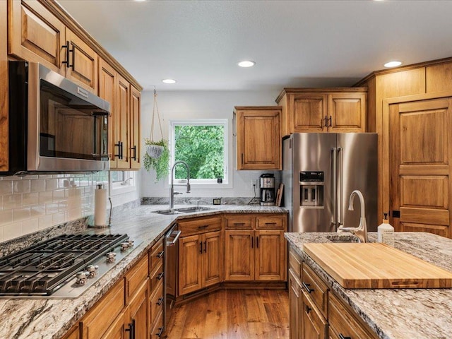 11034 Forest View Ct SW, Nisswa, MN 56468 - kitchen with appliances with stainless steel finishes, brown cabinetry, wood finished floors, decorative backsplash, and recessed lighting