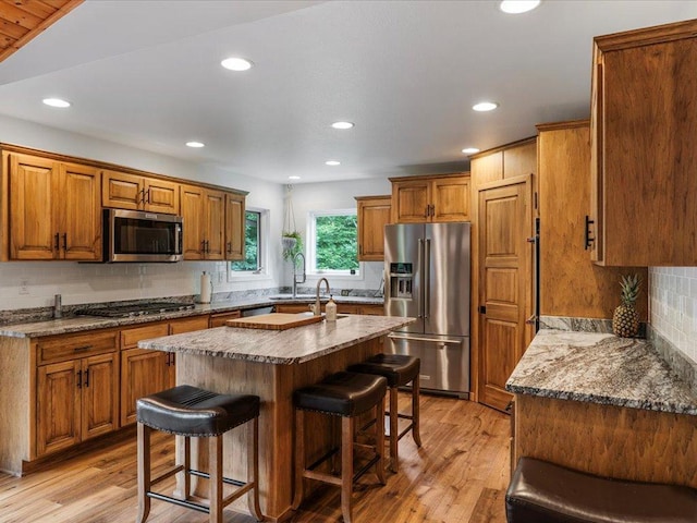 11034 Forest View Ct SW, Nisswa, MN 56468 - kitchen featuring appliances with stainless steel finishes, a kitchen bar, brown cabinetry, decorative backsplash, and recessed lighting