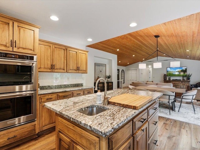 11034 Forest View Ct SW, Nisswa, MN 56468 - kitchen featuring double oven, open floor plan, light wood-style flooring, vaulted ceiling, and light stone countertops
