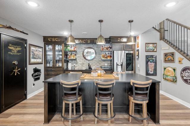4452 167th Ave NW, Andover, MN 55304 - indoor bar featuring stainless steel refrigerator with ice dispenser, light wood-style flooring, decorative light fixtures, a textured ceiling, and stairs