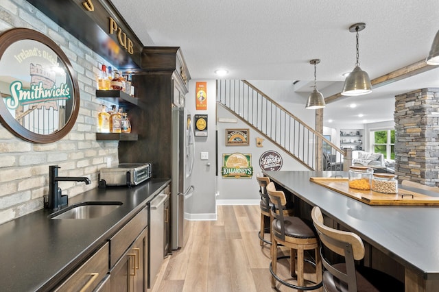 4452 167th Ave NW, Andover, MN 55304 - kitchen featuring light wood-style floors, dark countertops, a textured ceiling, decorative light fixtures, and dishwasher