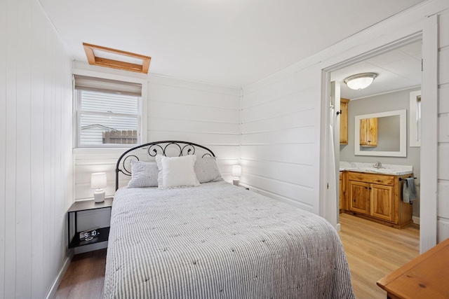 7315 120th St NW, Annandale, MN 55302 - bedroom with attic access, light wood-style floors, ensuite bathroom, wood walls, and ornamental molding