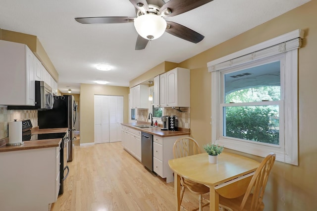 6788 147th St W, Savage, MN 55378 - kitchen featuring stainless steel appliances, backsplash, white cabinetry, light wood-style flooring, and a ceiling fan