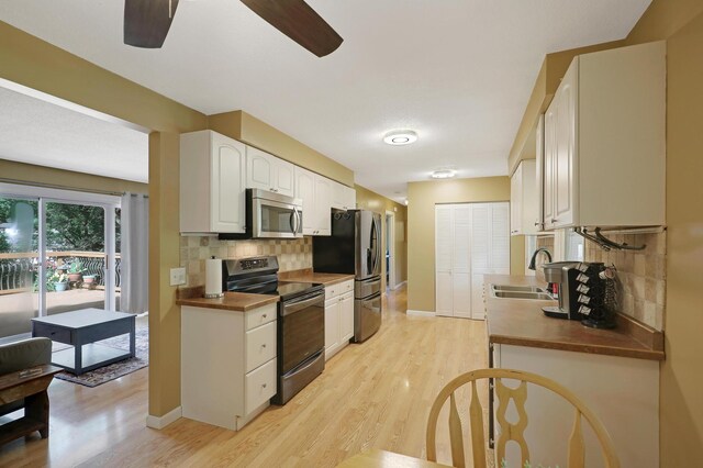 6788 147th St W, Savage, MN 55378 - kitchen with stainless steel appliances, a ceiling fan, light wood-style floors, tasteful backsplash, and white cabinetry