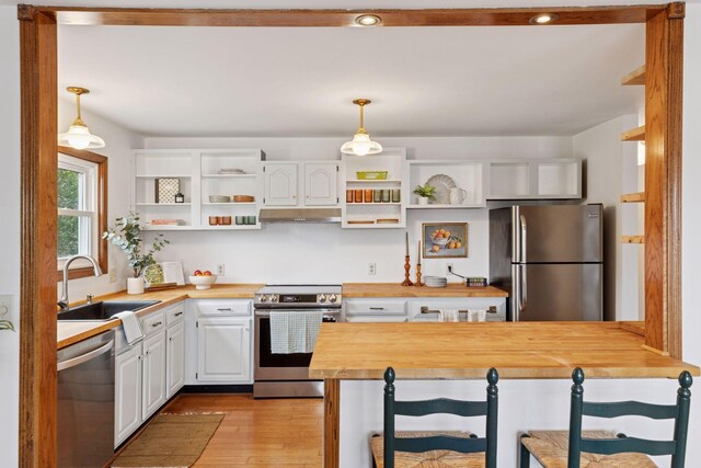 301 3rd St S Unit 302, Stillwater, MN 55082 - kitchen with appliances with stainless steel finishes, butcher block countertops, under cabinet range hood, open shelves, and white cabinetry