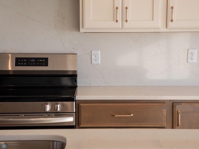 302 Neuman Blvd, Colfax, ND 58018 - kitchen featuring stainless steel range with electric cooktop, white cabinetry, light countertops, and tasteful backsplash