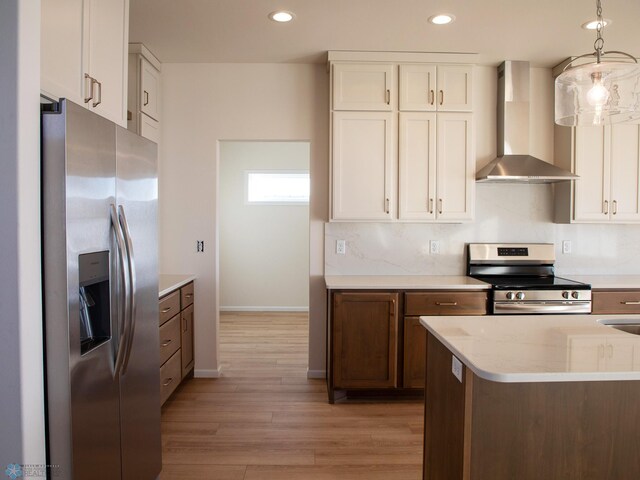 302 Neuman Blvd, Colfax, ND 58018 - kitchen featuring wall chimney exhaust hood, stainless steel appliances, light wood-style flooring, white cabinetry, and pendant lighting