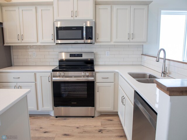 6310 83rd Ave S, Horace, ND 58047 - kitchen with stainless steel appliances, white cabinetry, light wood finished floors, and tasteful backsplash