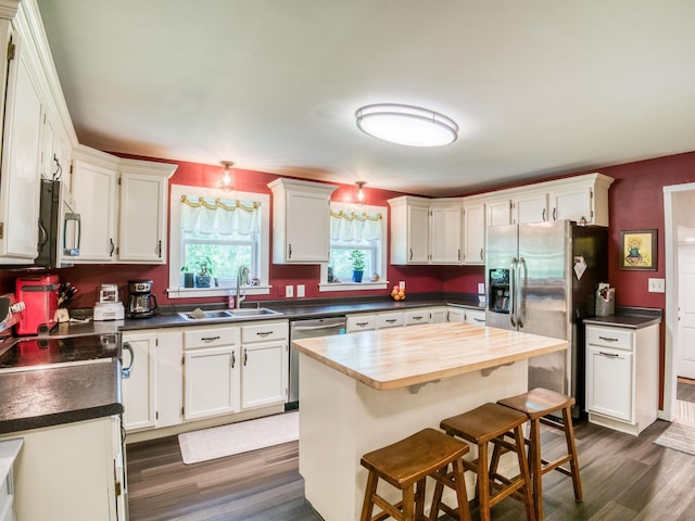 5936 Roosevelt Rd SE, Bemidji, MN 56601 - kitchen with appliances with stainless steel finishes, dark wood finished floors, white cabinetry, and a kitchen island