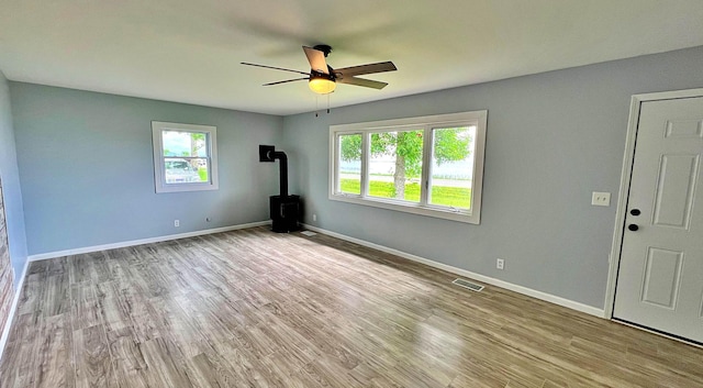 7165 US Highway 169, Garrison, MN 56450 - unfurnished living room with a wood stove, healthy amount of natural light, ceiling fan, and wood finished floors