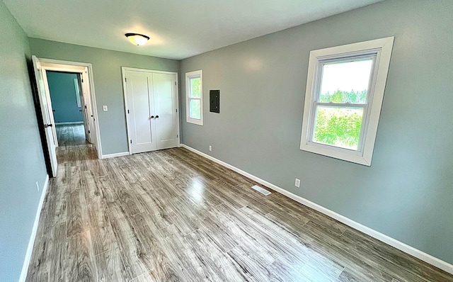 7165 US Highway 169, Garrison, MN 56450 - unfurnished bedroom featuring wood finished floors, electric panel, and a closet