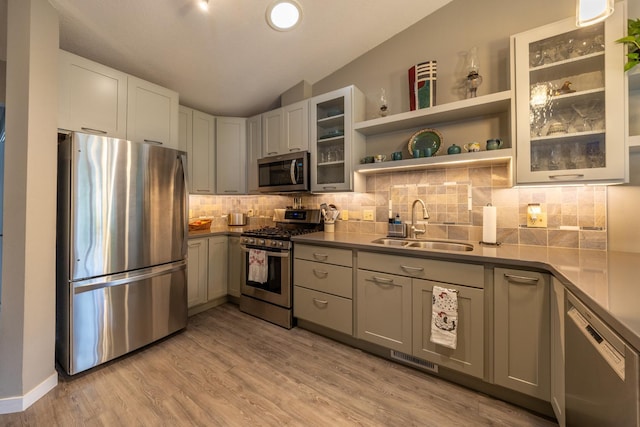 609 Main St E, Wabasha, MN 55981 - kitchen featuring stainless steel appliances, backsplash, lofted ceiling, glass insert cabinets, and light wood-style flooring