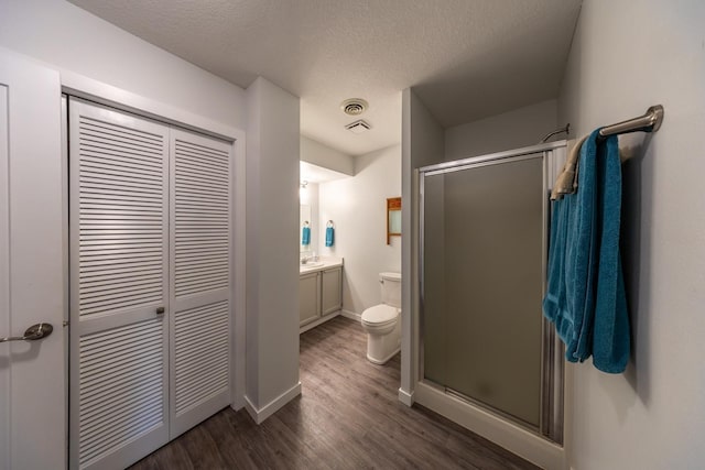 609 Main St E, Wabasha, MN 55981 - bathroom featuring a closet, a stall shower, vanity, wood finished floors, and a textured ceiling