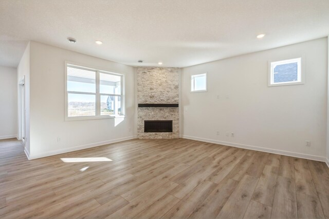 20264 Marsh Ct, Rogers, MN 55311 - unfurnished living room with light wood-type flooring, a stone fireplace, and recessed lighting