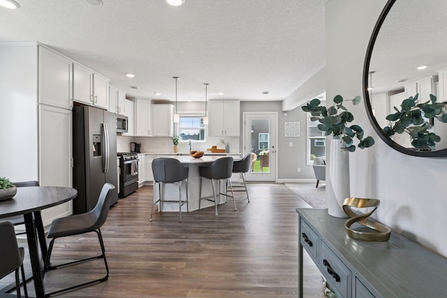 9462 Bridle Way, Victoria, MN 55386 - kitchen with stainless steel appliances, white cabinetry, a kitchen breakfast bar, dark wood-style flooring, and a center island