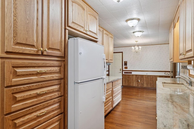 704 Highland Dr, New Prague, MN 56071 - kitchen with freestanding refrigerator, wallpapered walls, wainscoting, light stone countertops, and wood finished floors