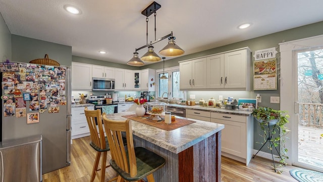 31340 Indigo Rd, Fountain, MN 55935 - kitchen featuring appliances with stainless steel finishes, light wood-type flooring, white cabinets, a breakfast bar, and decorative light fixtures