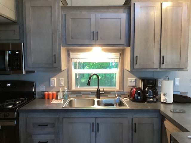 14275 Schuelke Beach Rd NW, Miltona, MN 56354 - kitchen with black gas stove, stainless steel microwave, and gray cabinetry