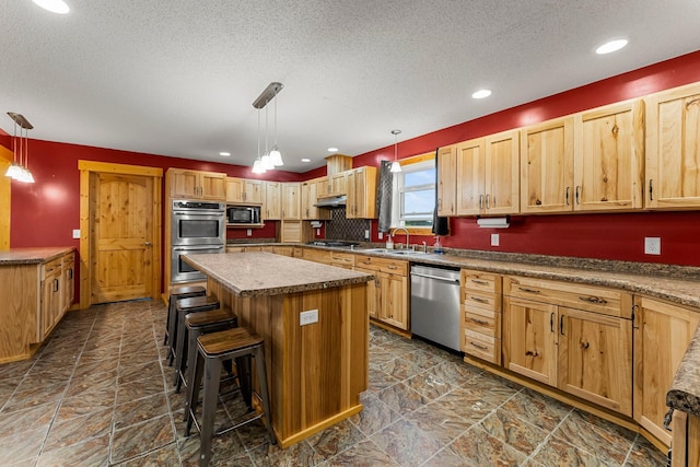42118 Lowden Ave, Sunrise Twp, MN 55032 - kitchen with appliances with stainless steel finishes, a textured ceiling, a center island, a kitchen bar, and hanging light fixtures