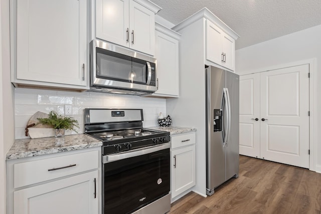 1418 Cedar Ln, Litchfield, MN 55355 - kitchen with appliances with stainless steel finishes, light wood finished floors, tasteful backsplash, white cabinets, and light stone counters