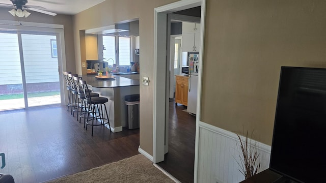 524 1st Ave SE, Wells, MN 56097 - kitchen featuring freestanding refrigerator, a kitchen bar, ceiling fan, and dark wood-type flooring