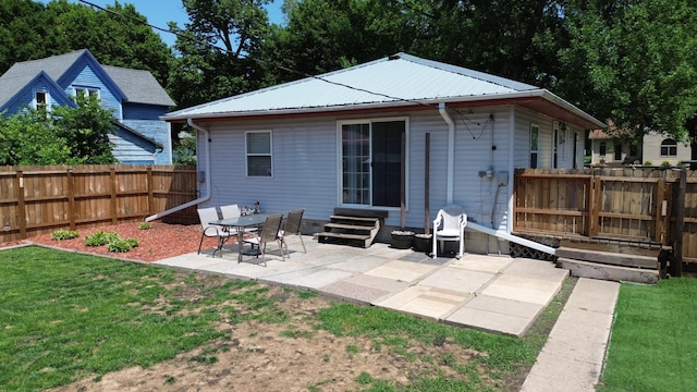 524 1st Ave SE, Wells, MN 56097 - rear view of property featuring entry steps, a patio area, a fenced backyard, and a metal roof