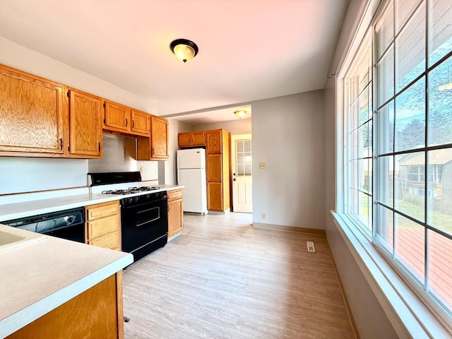 2112 Manitou Ave, Saint Paul, MN 55119 - kitchen with range with gas stovetop, freestanding refrigerator, plenty of natural light, and light wood-style floors