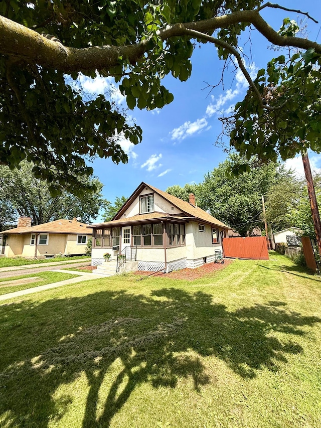 2112 Manitou Ave, Saint Paul, MN 55119 - view of front of property with a sunroom, a front yard, a chimney, and stucco siding