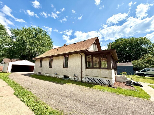 2112 Manitou Ave, Saint Paul, MN 55119 - view of property exterior featuring an outbuilding, stucco siding, a detached garage, a sunroom, and a shingled roof